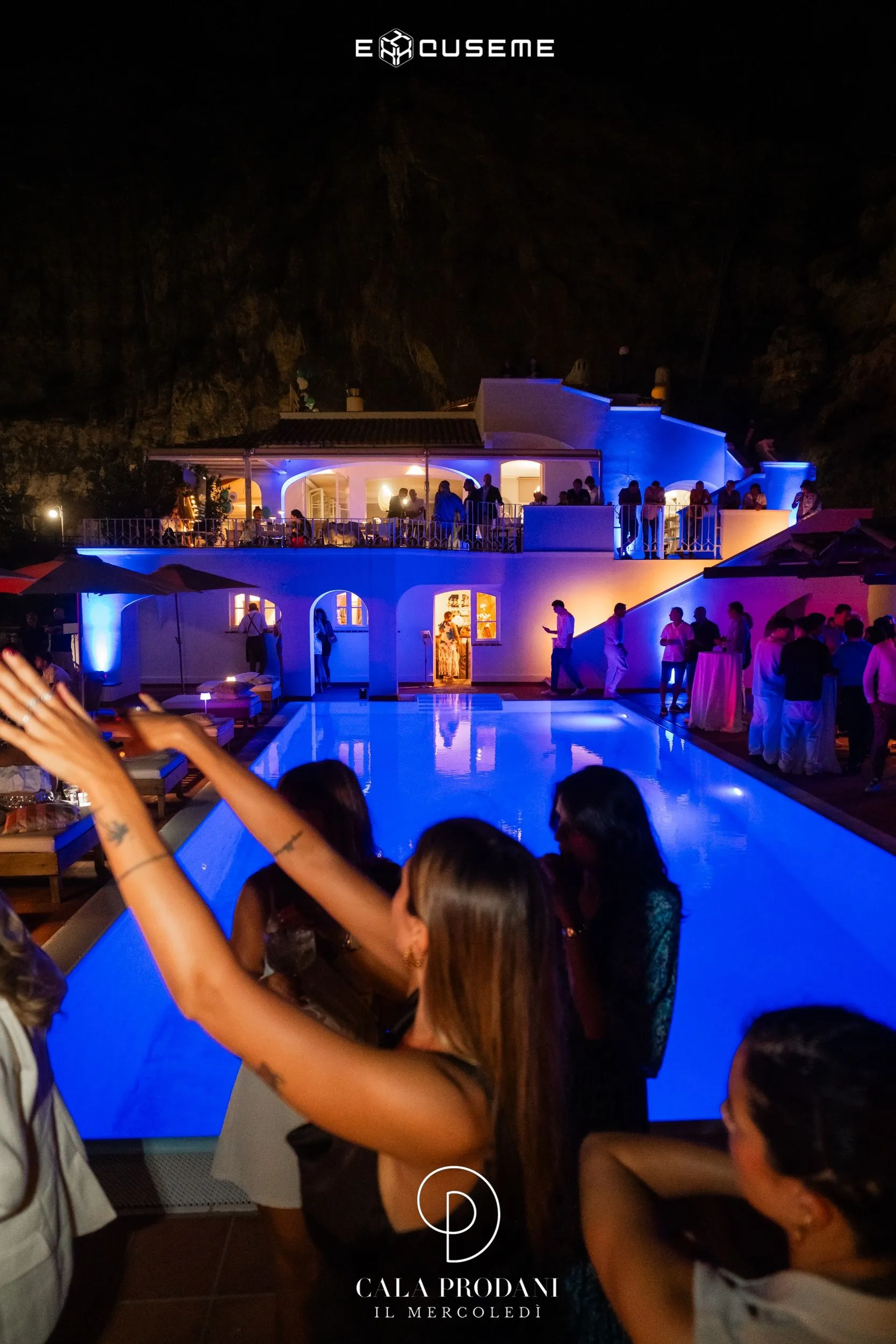Evento notturno con piscina illuminata sotto la scogliera